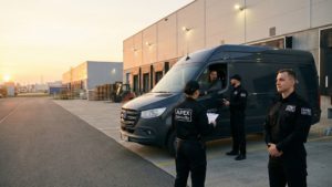 Apex Security Team sichert einen Transporter auf dem Gelände eines Logistikzentrums ab, Sicherheitsmitarbeiter stehen rund um das Fahrzeug und überprüfen gemeinsam mit dem Fahrer die Unterlagen.
